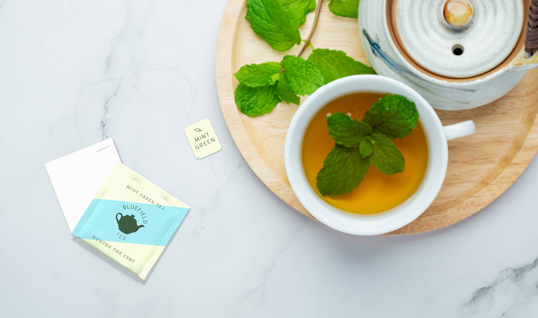 An above view of a tea bag on a table with a cup and tea pot